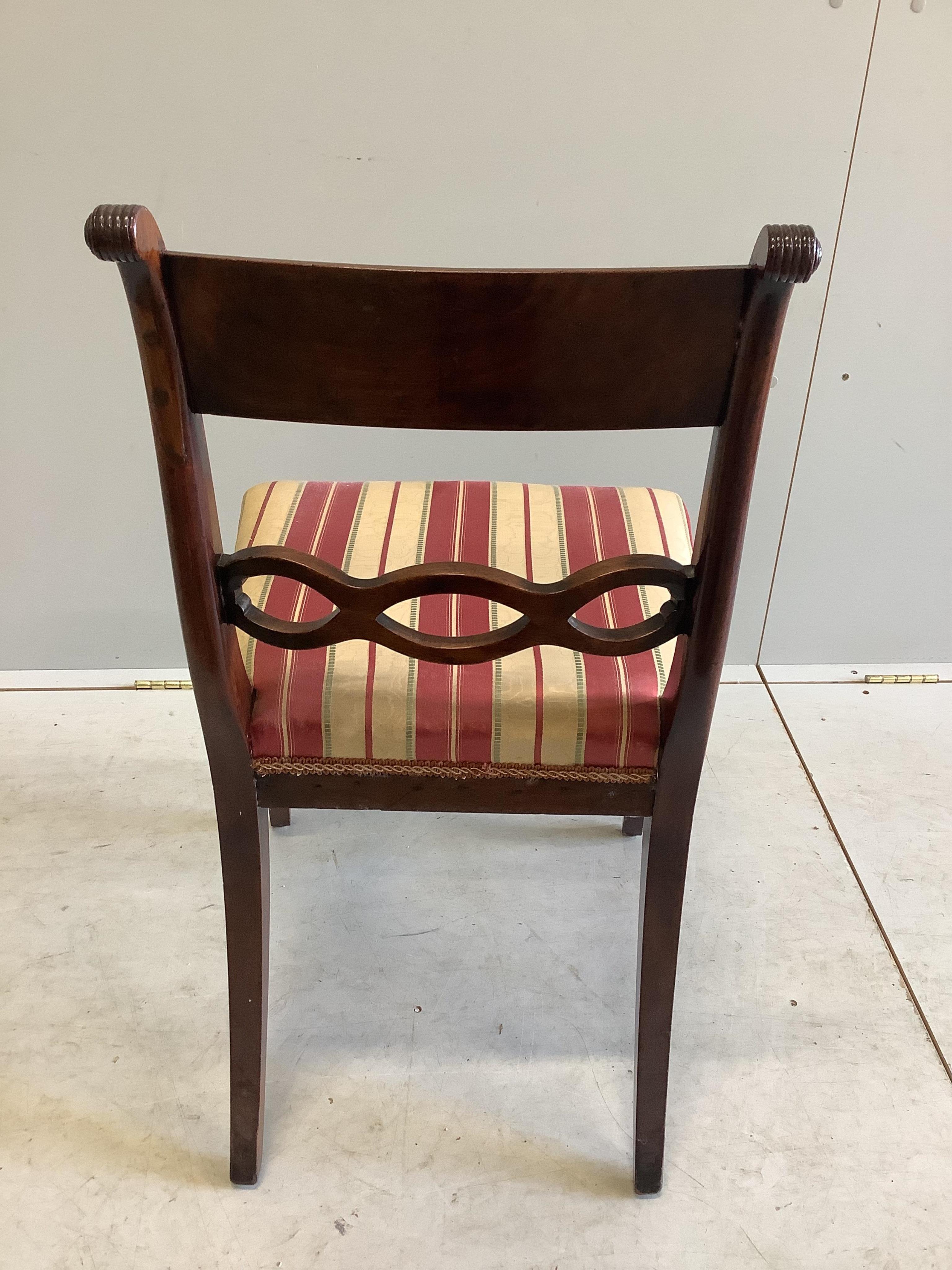 A George III mahogany oval pedestal dining table with brass claw feet, width 152cm, depth 105cm, height 71cm, together with a set of six Regency mahogany sabre leg dining chairs. Condition - fair to good